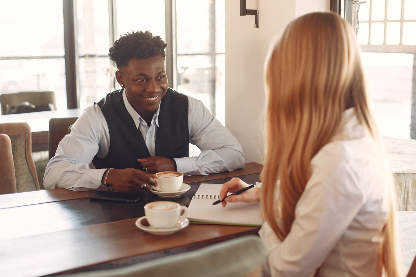 Two people discuss their notes over coffee at a cafe table.