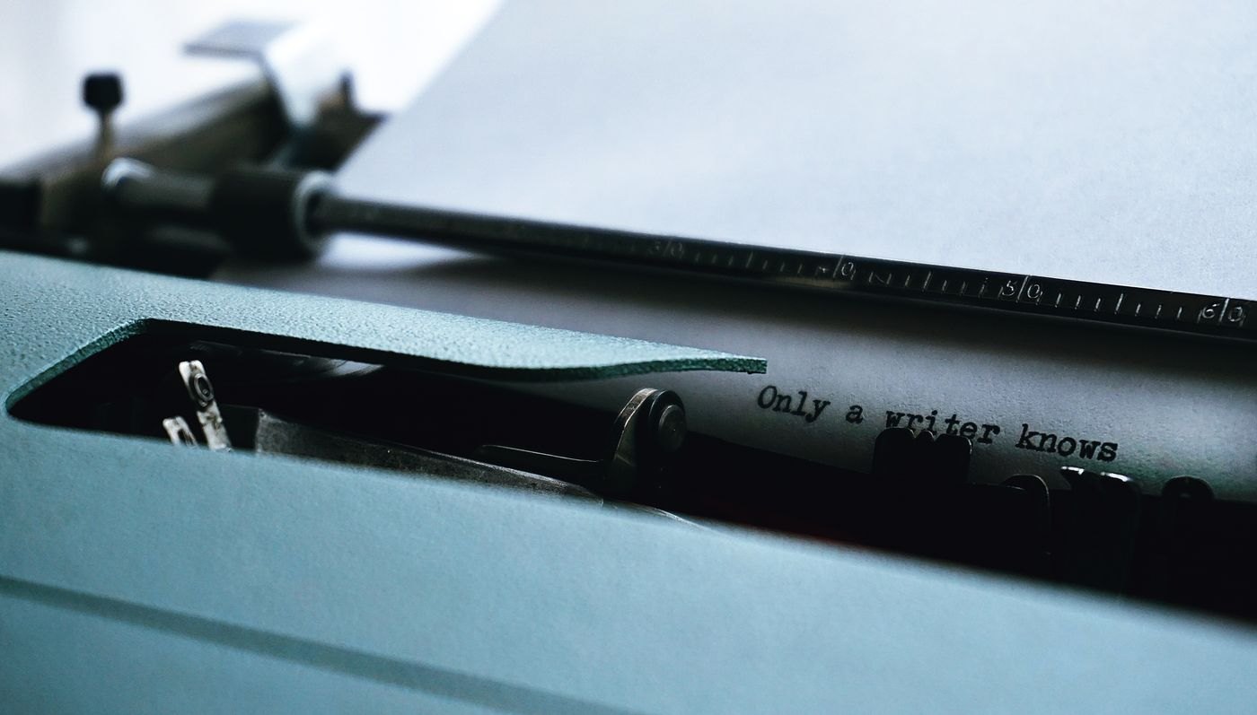A typewriter holds a page with a short opening line.