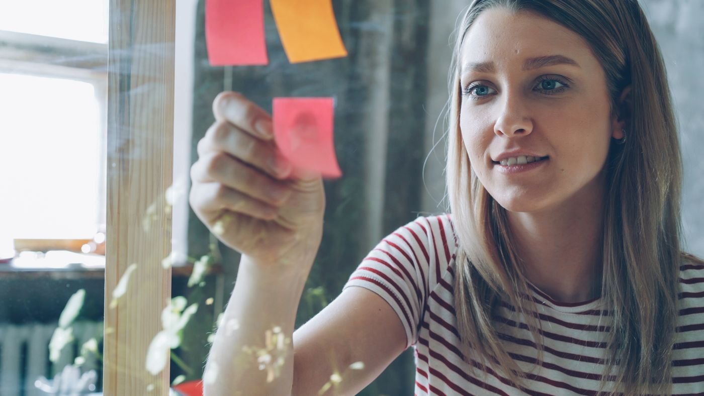 A person arranges written ideas on sticky notes.