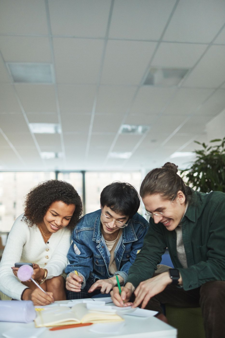 Three people work together on written notes around a table.