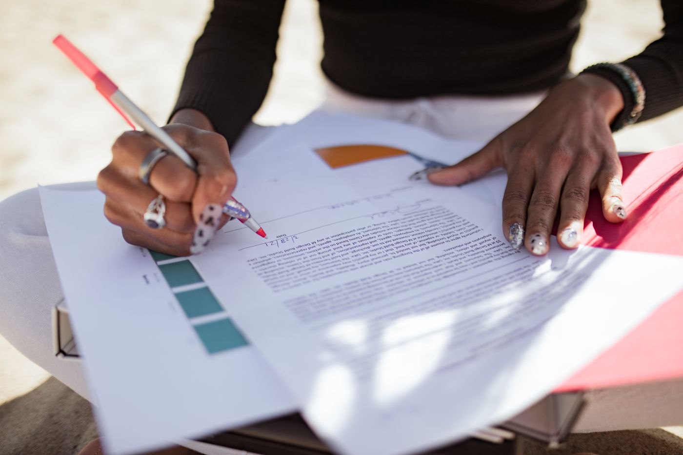 A red pen marks revisions on printed pages outdoors.