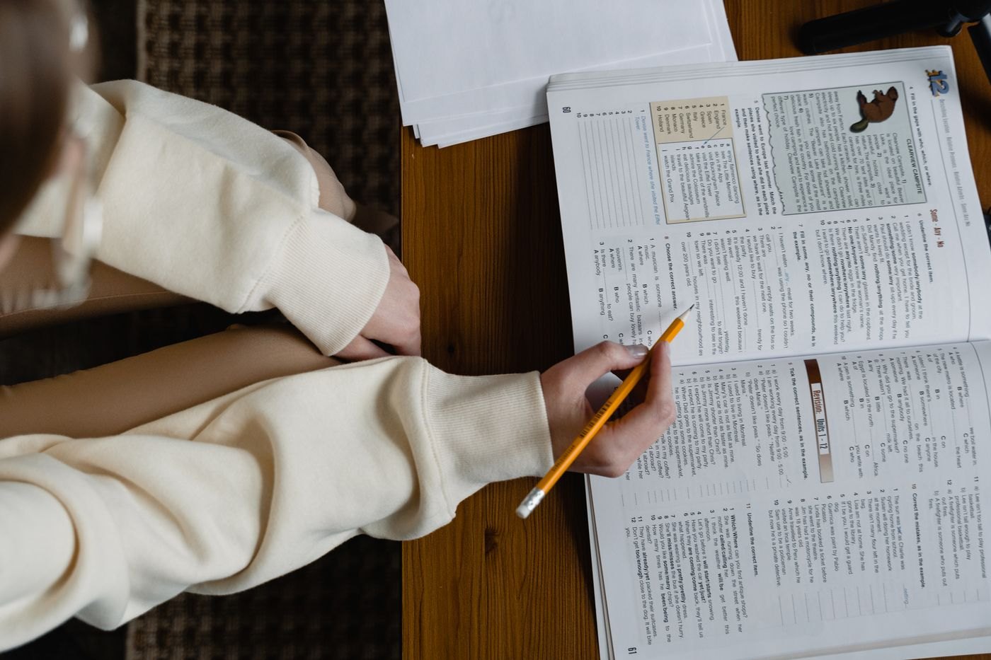 A reader follows a passage in an open book with a pencil.