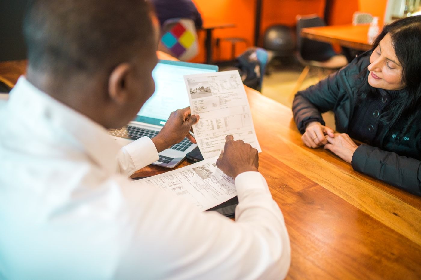 Two people discuss the contents of a printed document.