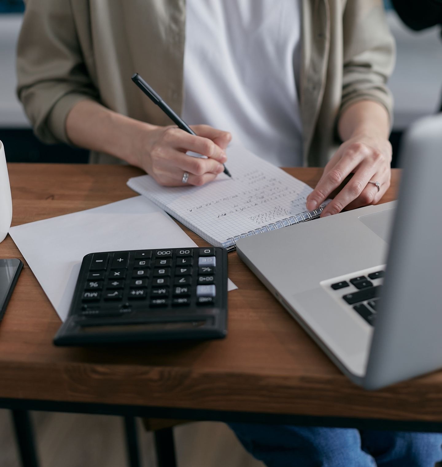 Calculator and notebook beside a laptop