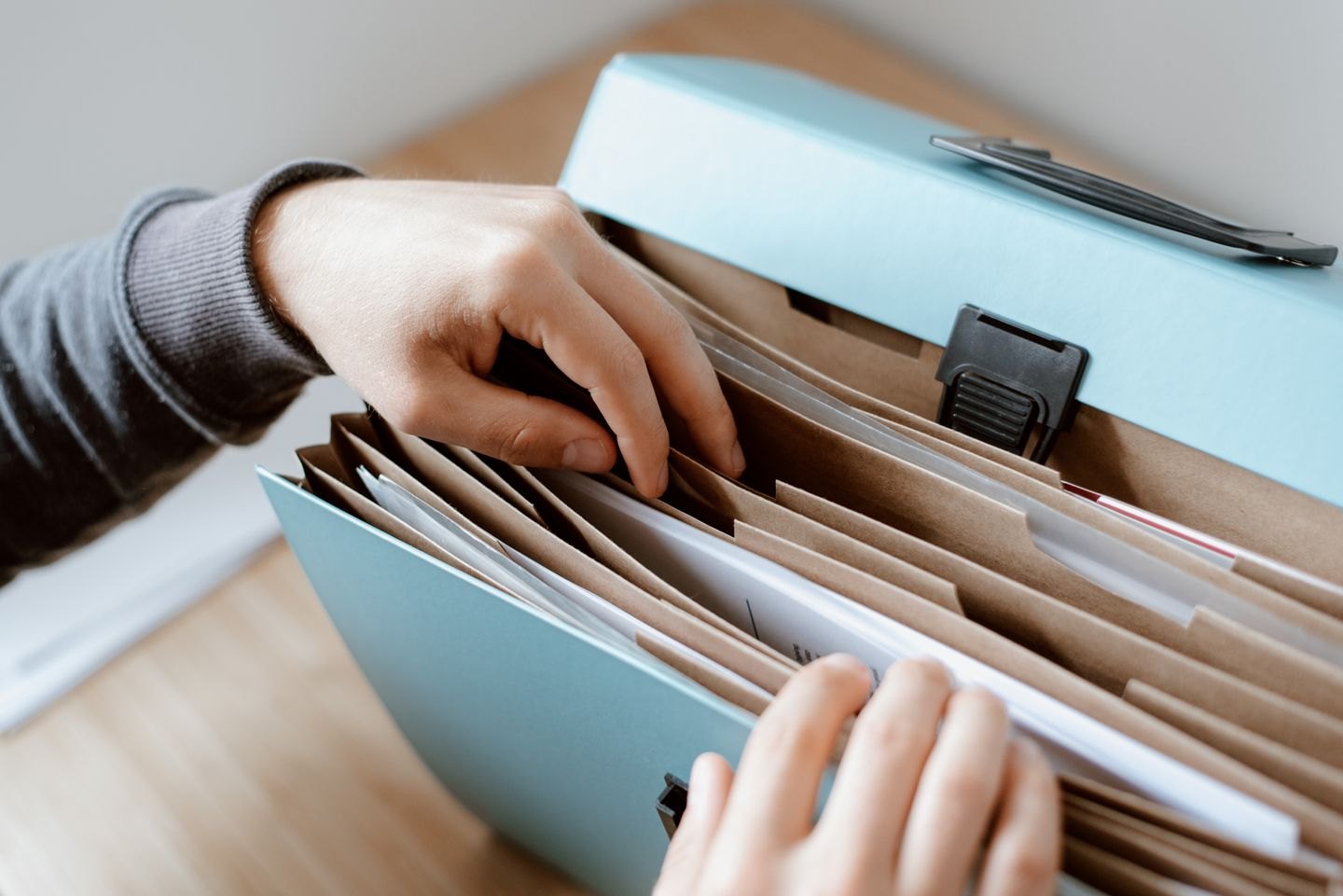 Hands selecting papers from an expanding file