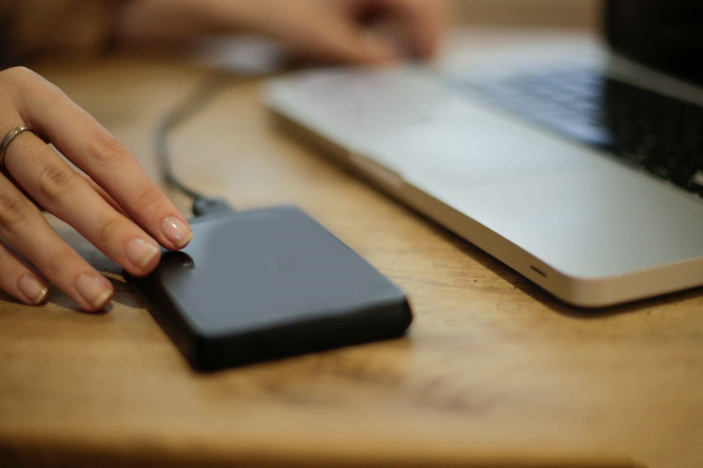 Hand connecting an external drive to a laptop