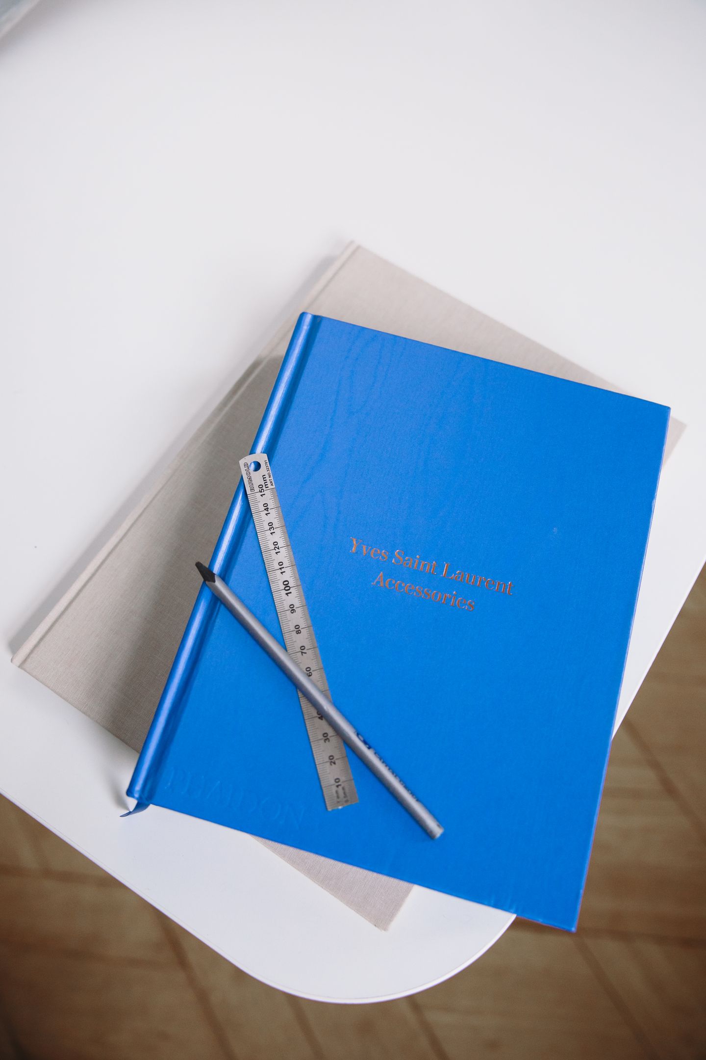 Two hardcover books with a metal ruler and pencil across the blue cover