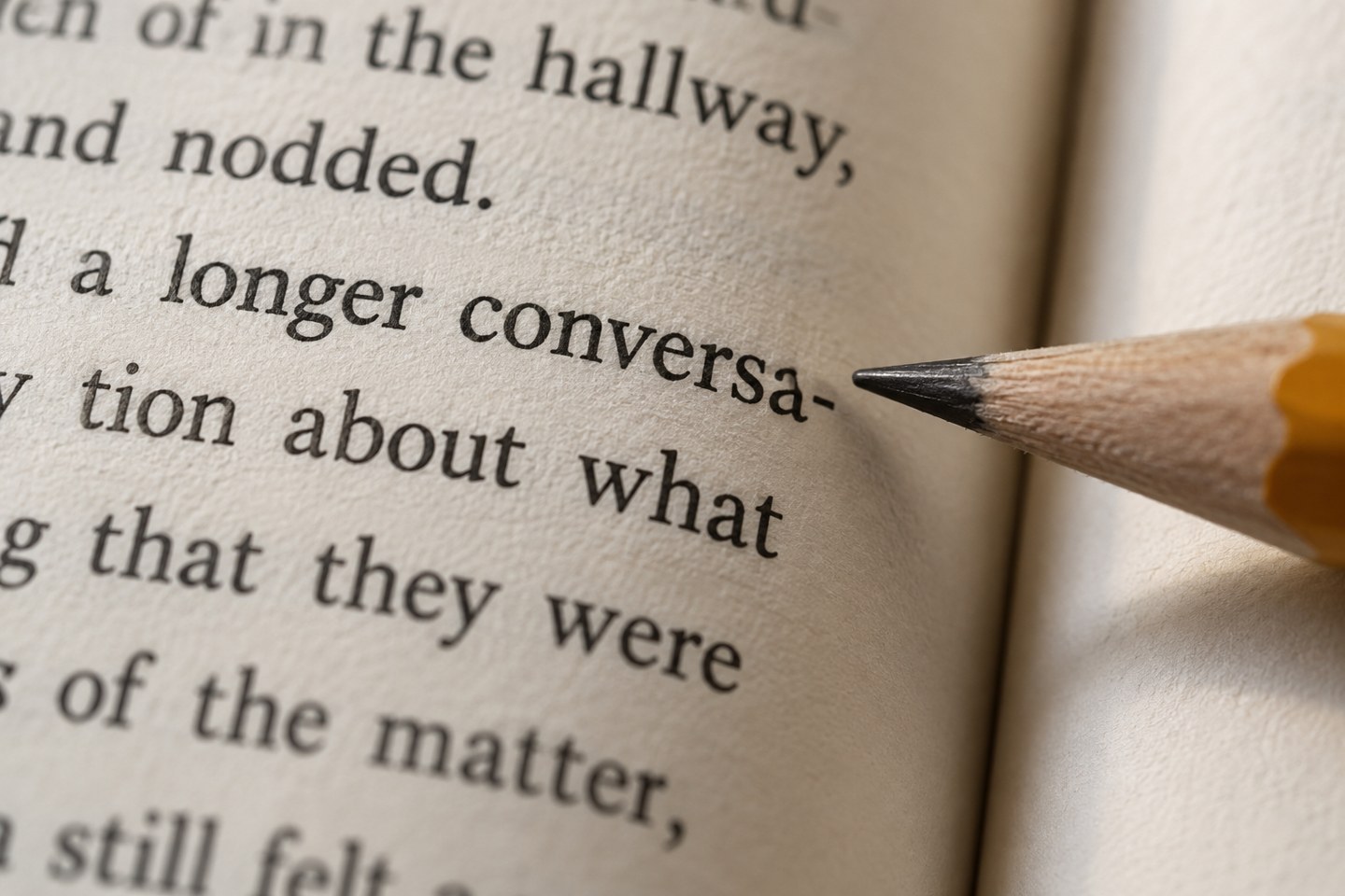 Pencil pointing to a hyphenated word at the end of a printed line