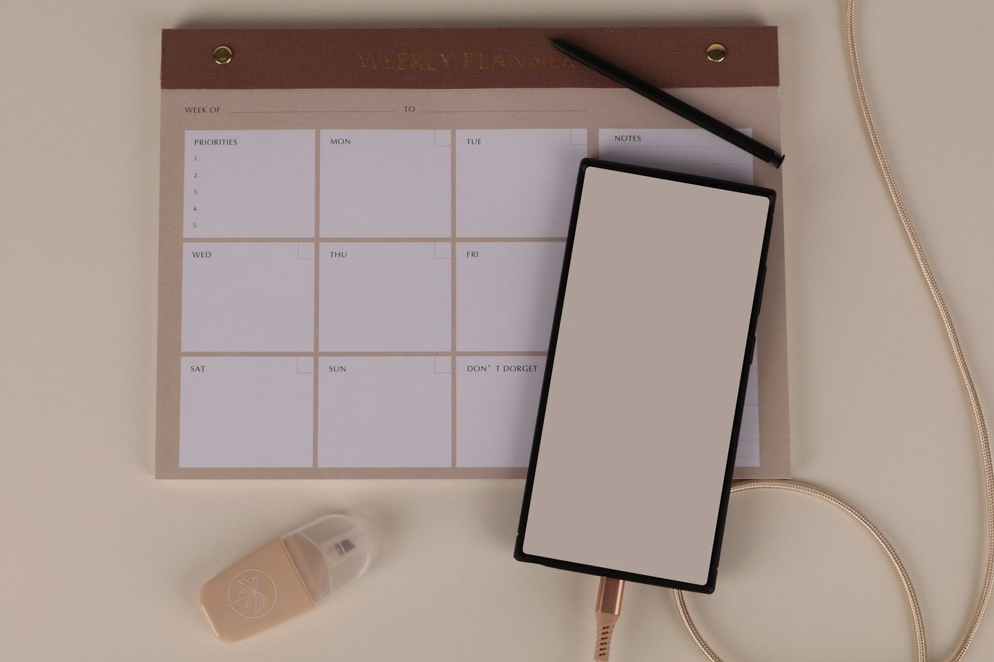 A weekly planner beside a tablet, mouse and stationery.