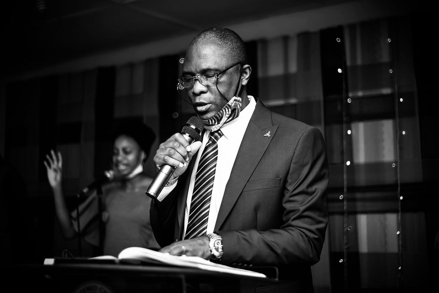 A man reading from a book while holding a microphone.