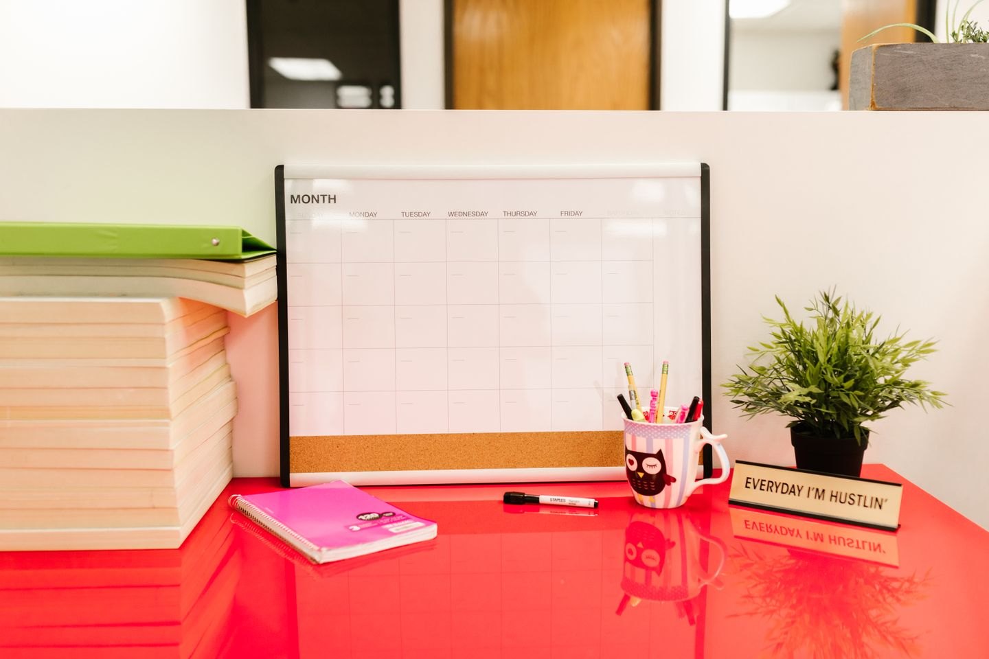 A calendar beside books and stationery on a desk.