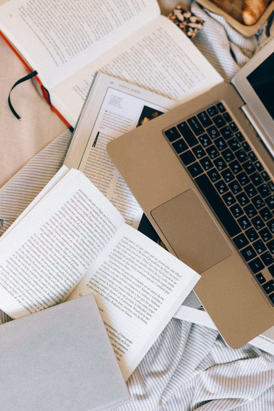 Open research books surrounding a laptop.