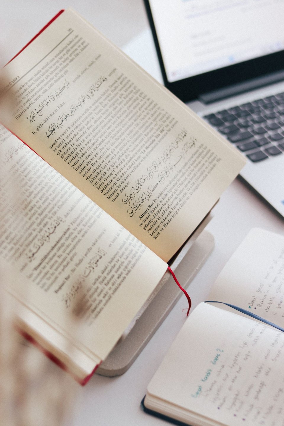 An open book and handwritten notebook beside a laptop document.