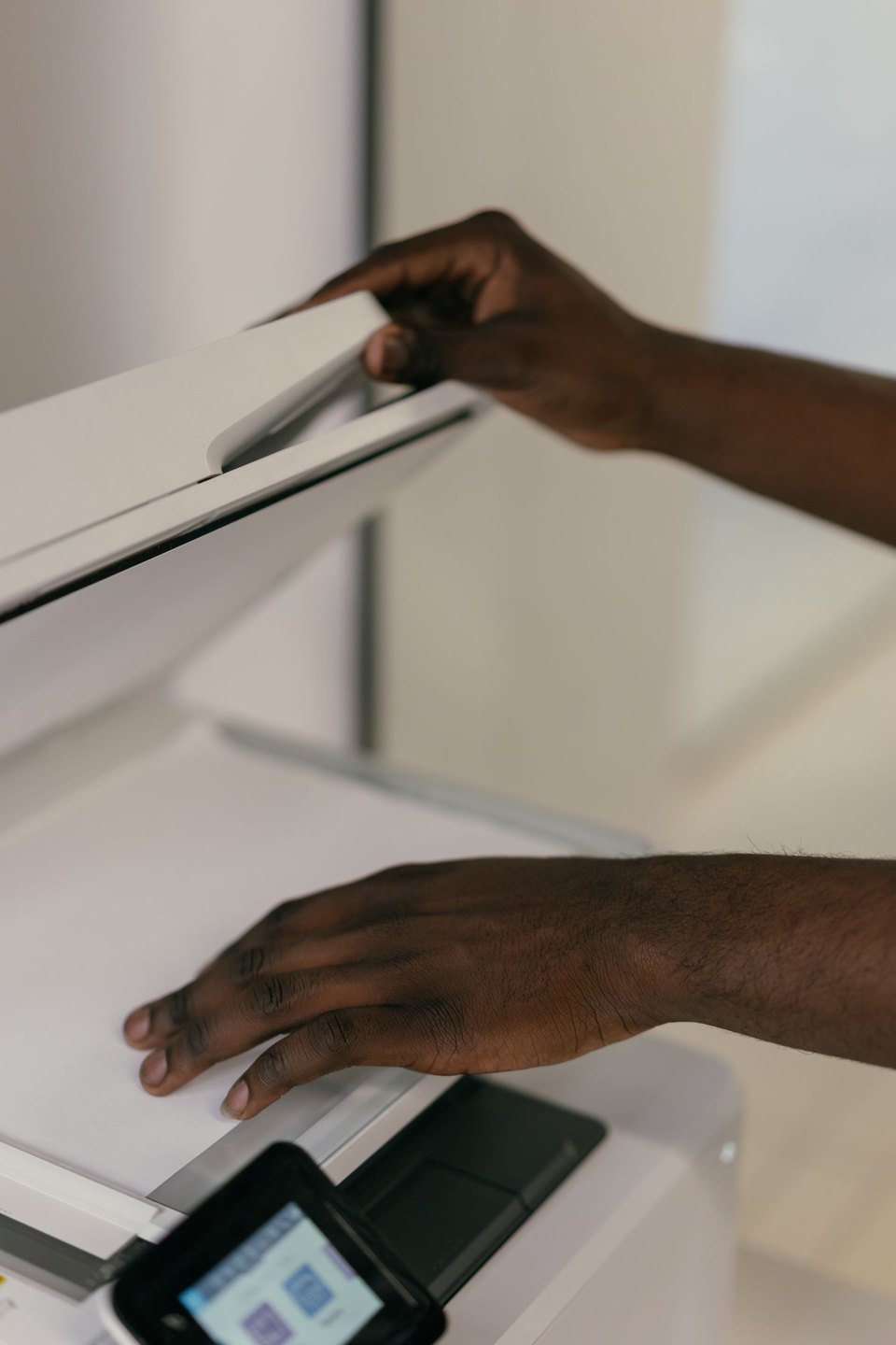 Hands placing a paper document on a scanner.
